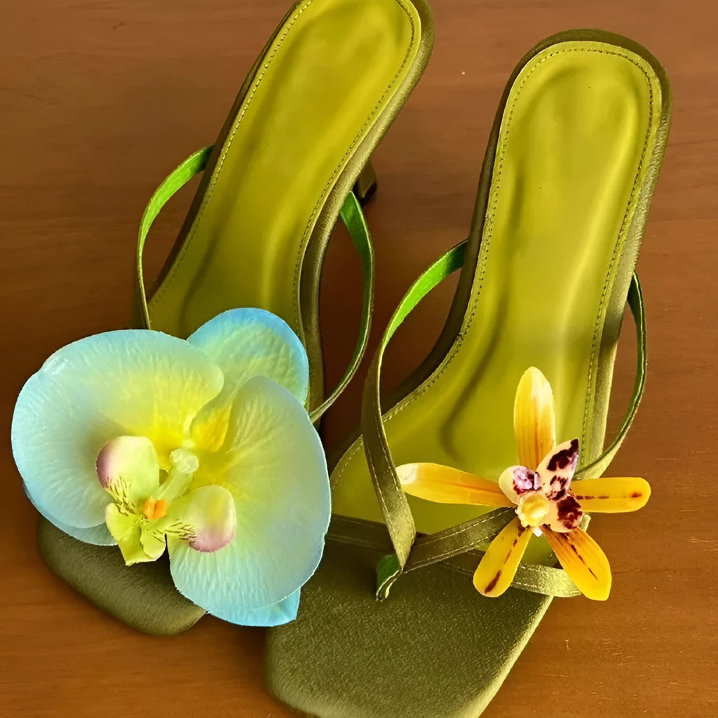 Women's black asymmetric floral high-heel sandals with a square toe and calf leather upper.