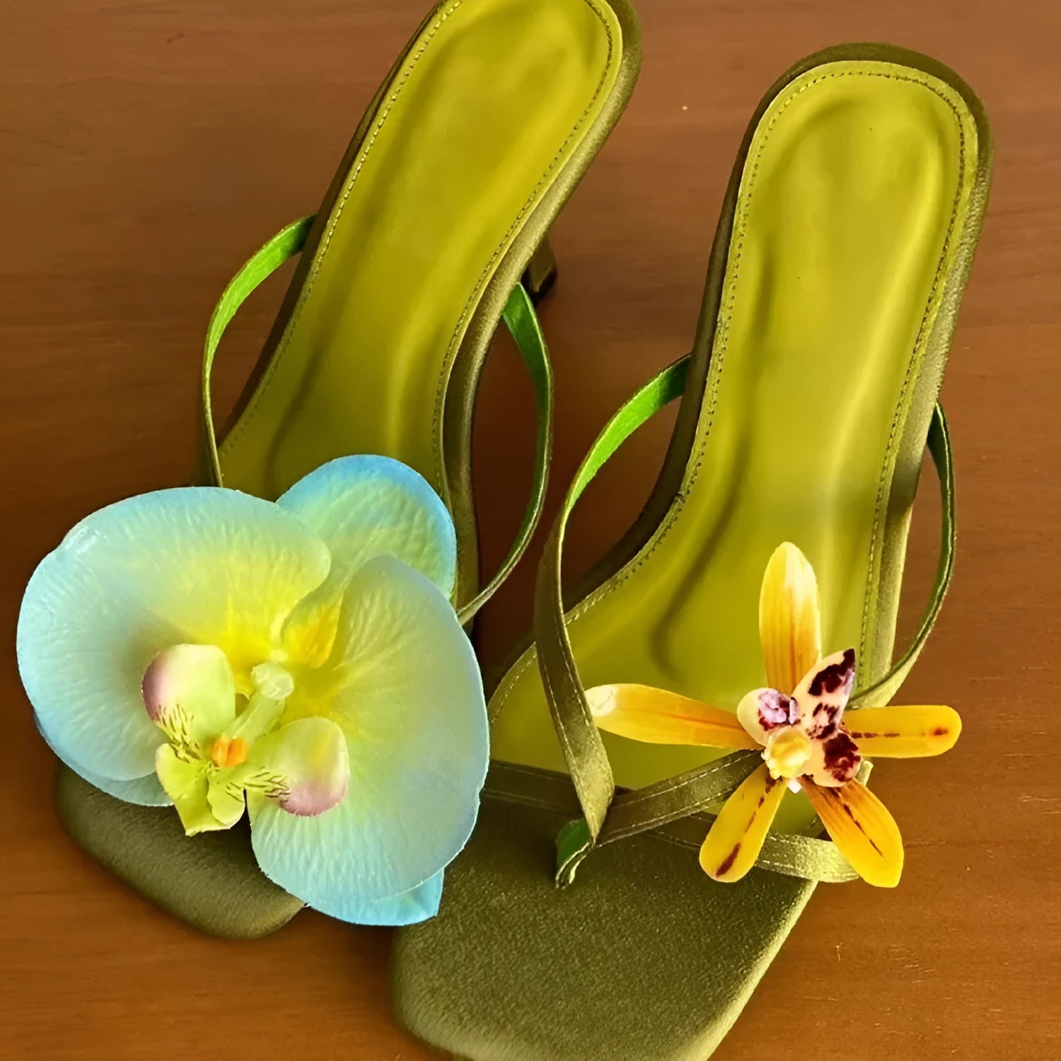 Women's black asymmetric floral high-heel sandals with a square toe and calf leather upper.