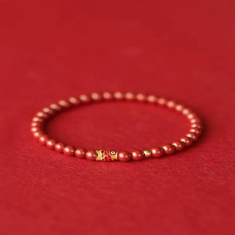 Natural cinnabar koi bracelet with golden ball in national style on a wrist.