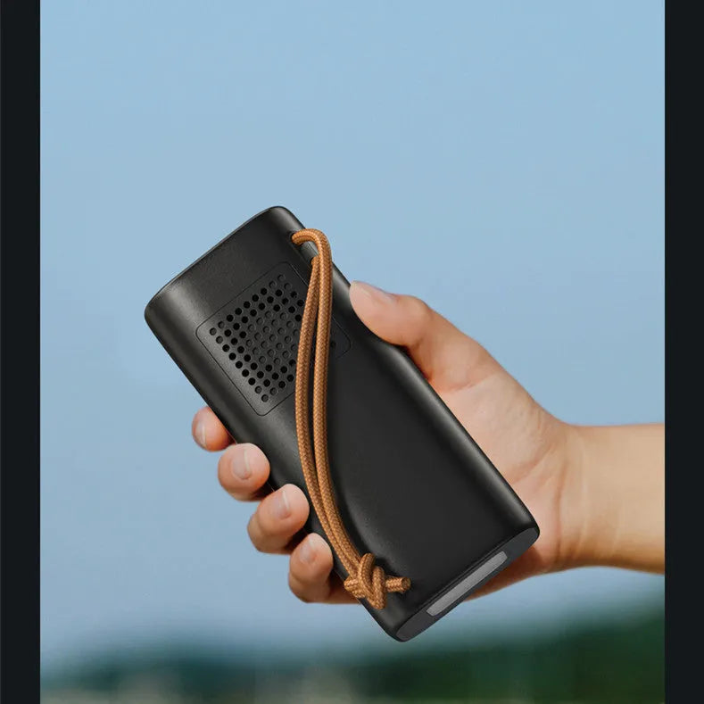 Black portable power bank with solar panel, showing USB ports and car charging socket