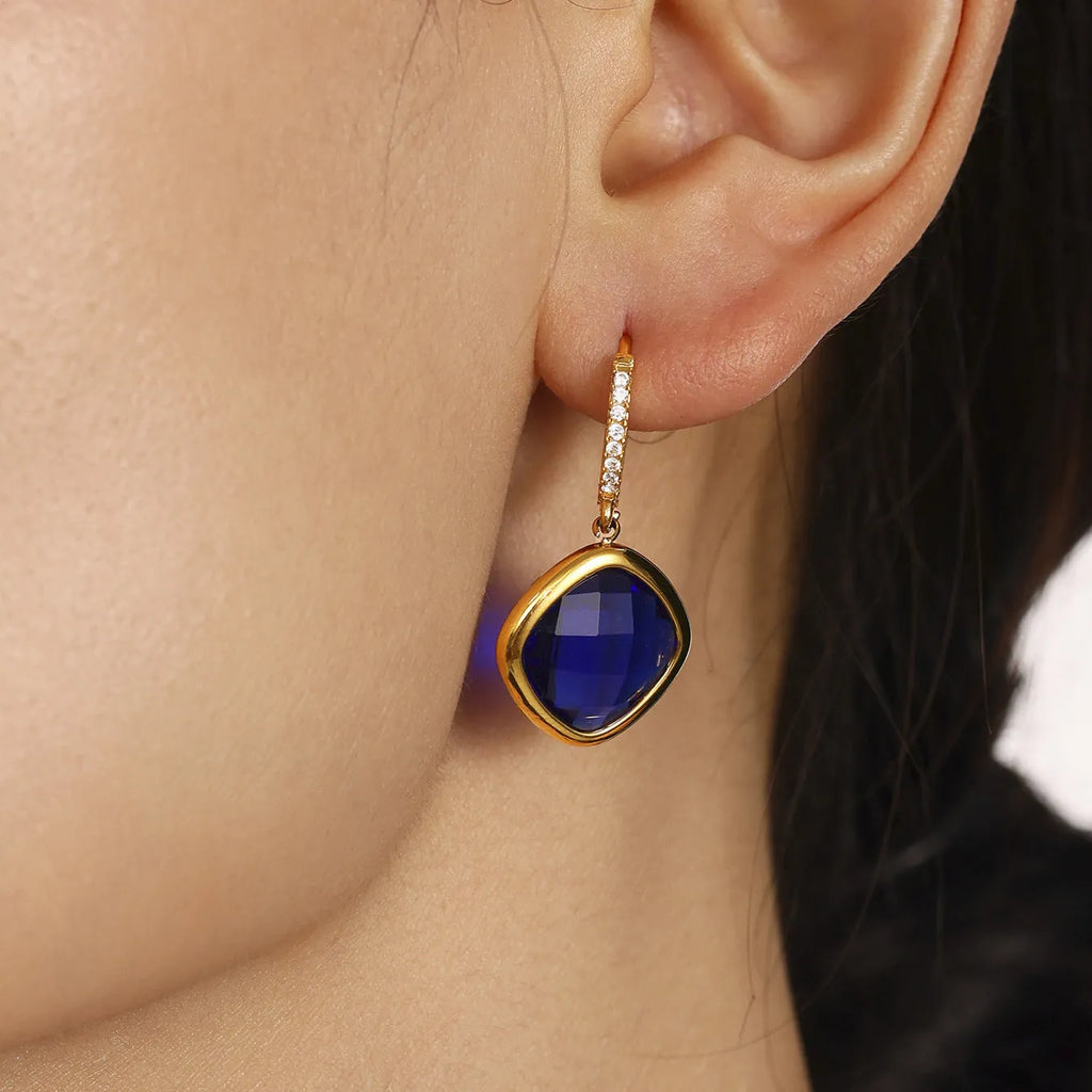 Mioli transparent cut Czech glass geometric square stud earrings in gold tone with blue zircon centre stone on white background
