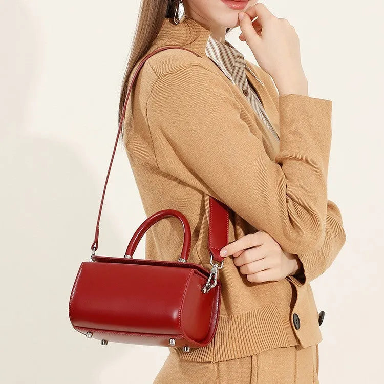 Women's leather crossbody bag in clamshell design showing internal phone and file pockets.