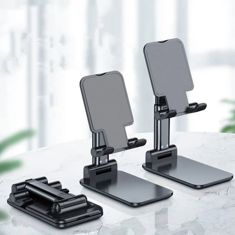 White folding telescopic mobile phone bracket holding a smartphone on a desktop.