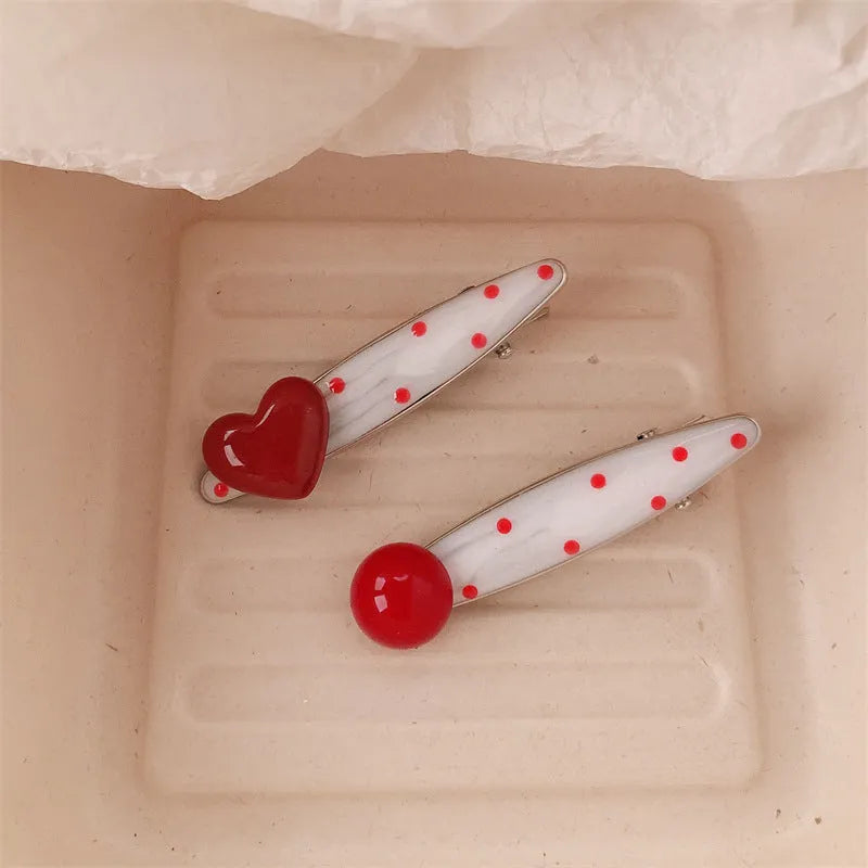 Red love heart-shaped plastic hair clip with retro dots and a willow leaf silhouette on a white background.