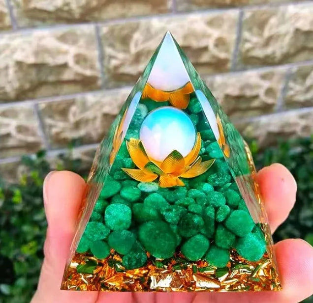 Clear epoxy resin pyramid ornament with natural crystal gravel inside on a wooden surface.