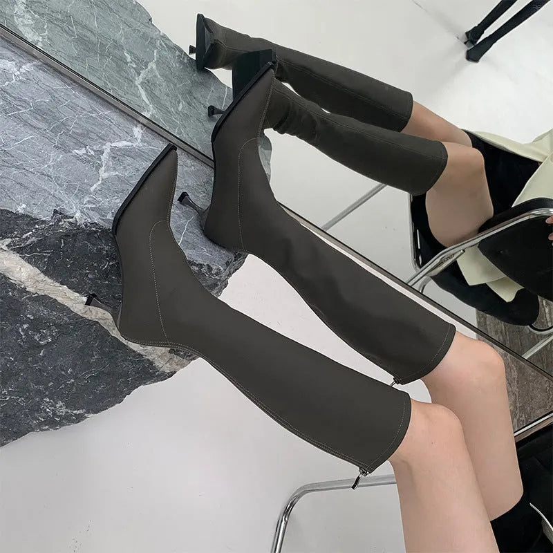 Women's black below the knee boots with pointed toe and stiletto heel, back zipper closure visible
