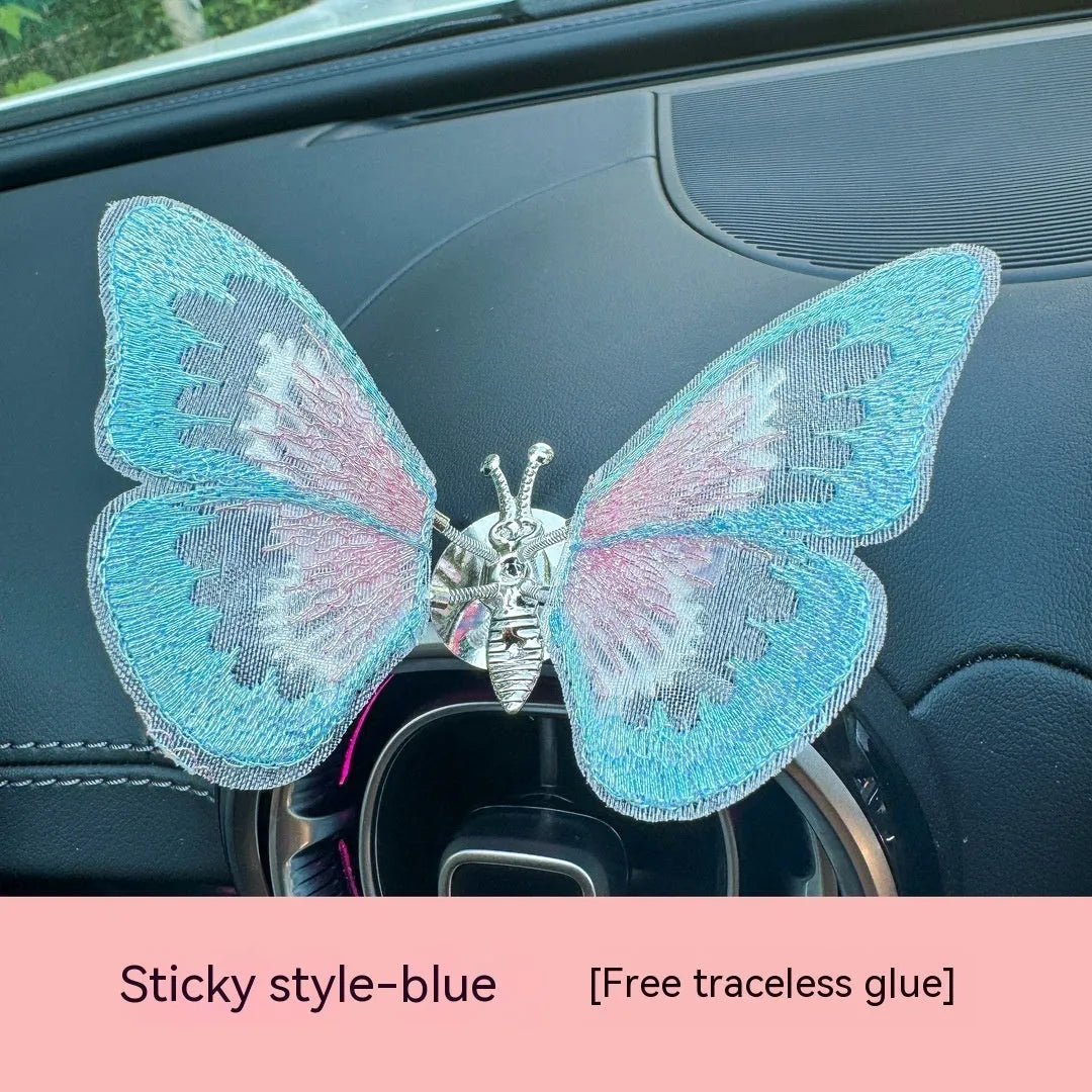 Fabric embroidered butterfly car air vent decoration in multiple colour options on a dashboard.