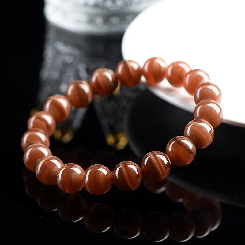 Natural old mine rhodochrosite round bead bracelet with Ruyi detail on a wrist.