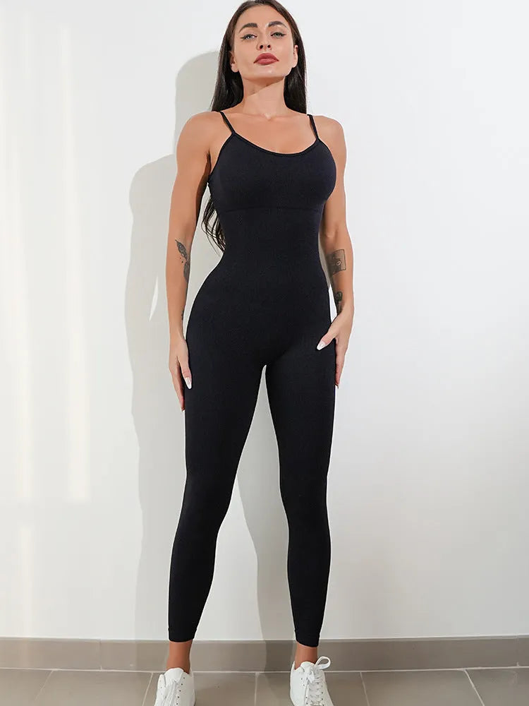 A woman wearing a black sleeveless unitard jumpsuit with spaghetti straps, showcasing its tight fit and backless design.