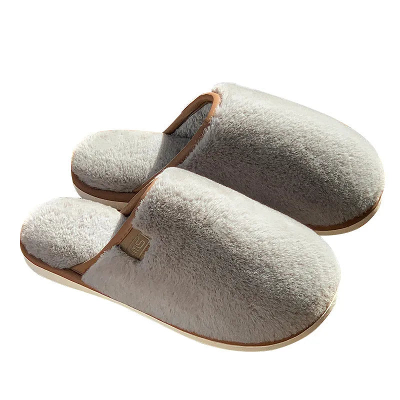 Solid colour winter plush slippers with non-slip PVC soles on a wooden floor