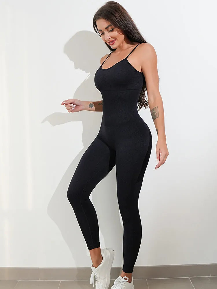 A woman wearing a black sleeveless unitard jumpsuit with spaghetti straps, showcasing its tight fit and backless design.