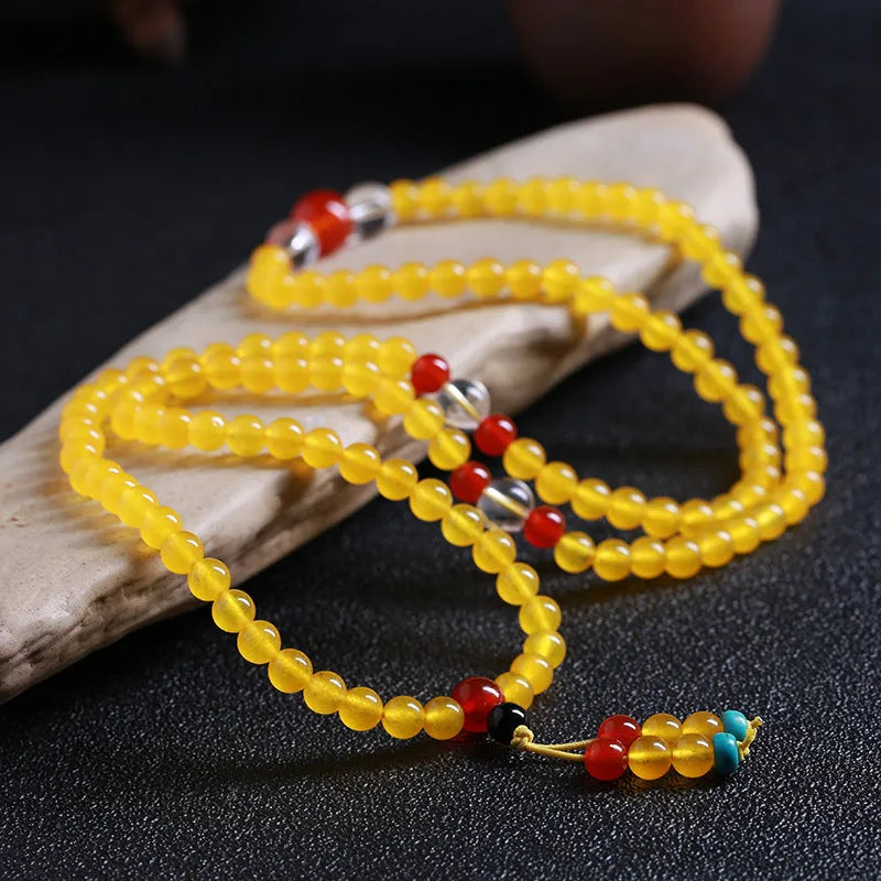 Women's geometric crystal necklace with lucky cat charm alongside 108 agate and canary stone beads