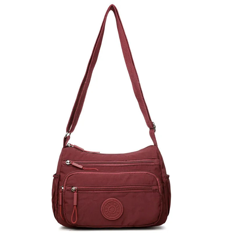 Grey water-repellent nylon crossbody bag showing outer pocket and internal organiser compartments.
