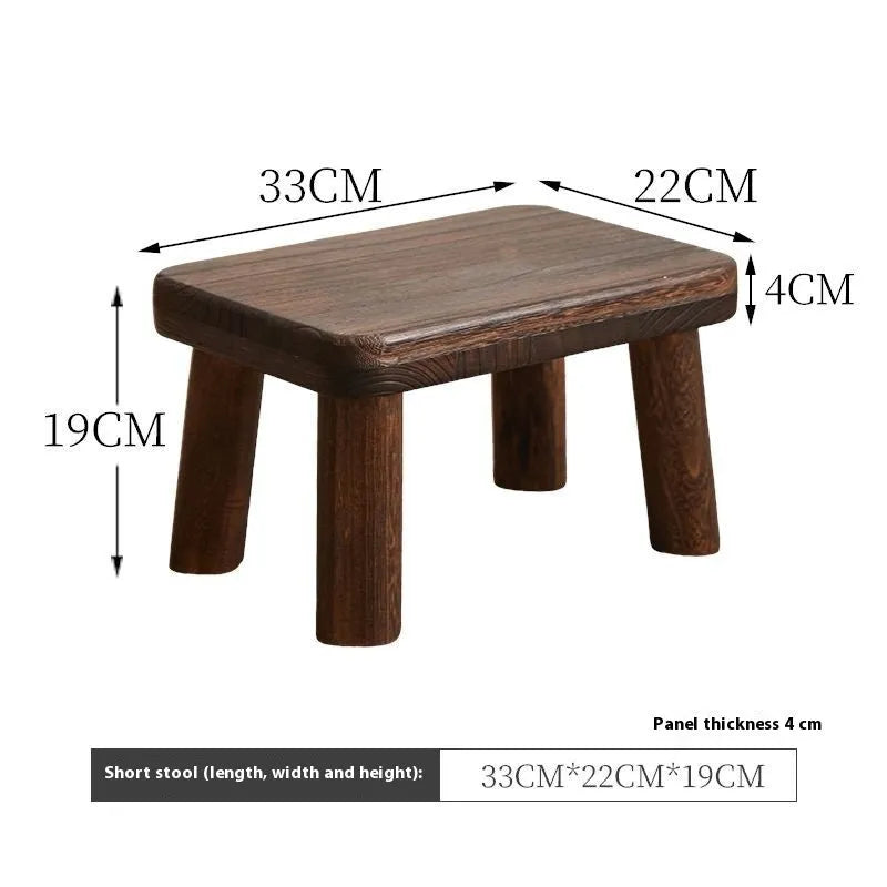 Solid wood distressed finish changing stool with bracket structure legs in a living room setting.