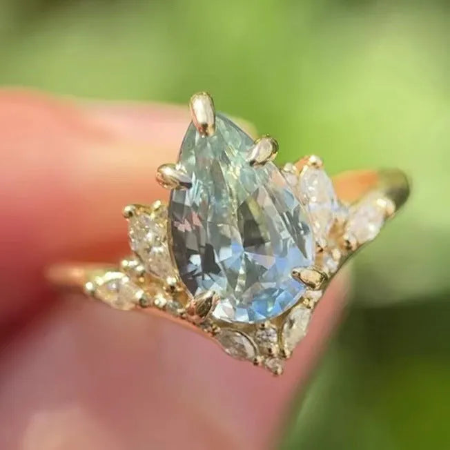 Gold alloy floral ring with aquamarine crystal centre on white background