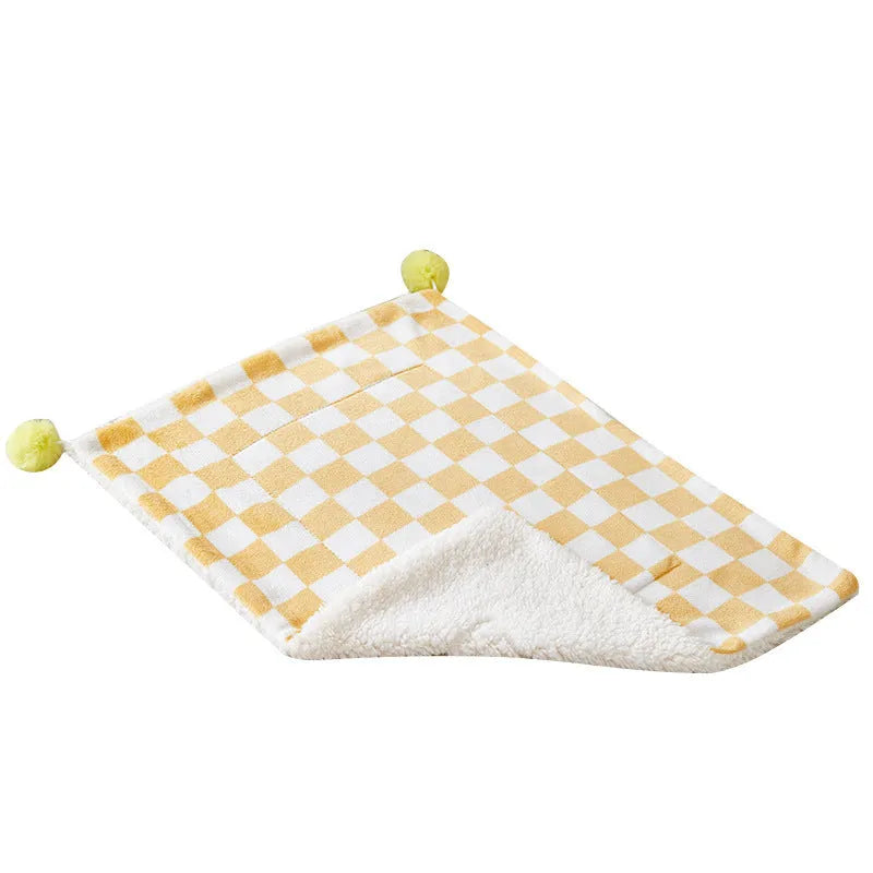 Soft plaid pattern pet blanket with fur ball decoration on a sofa