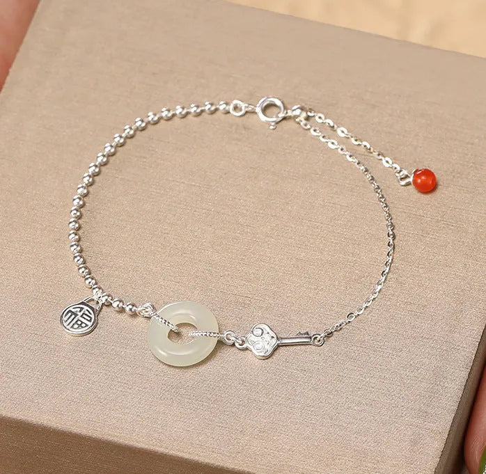 Women's silver bracelet with a geometric Hetian jade Wishful Blessings charm on a white background.