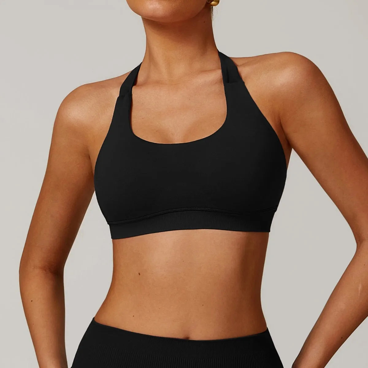 Women's black halter-style sports bra with removable pads for yoga and workout.