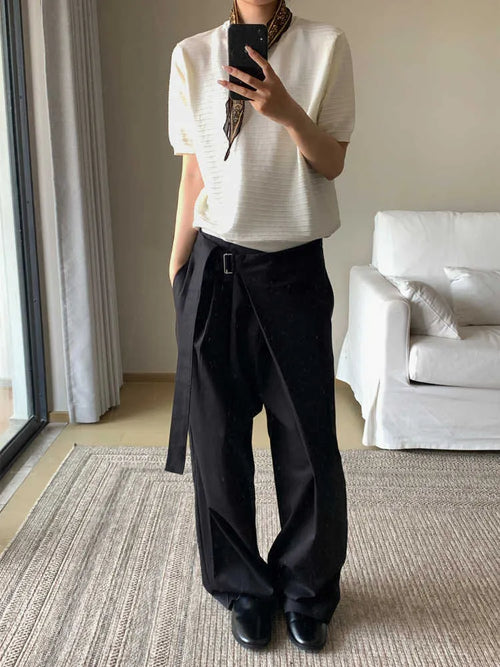Black single pleated straight-leg trousers with an adjustable waistband on a hanger.
