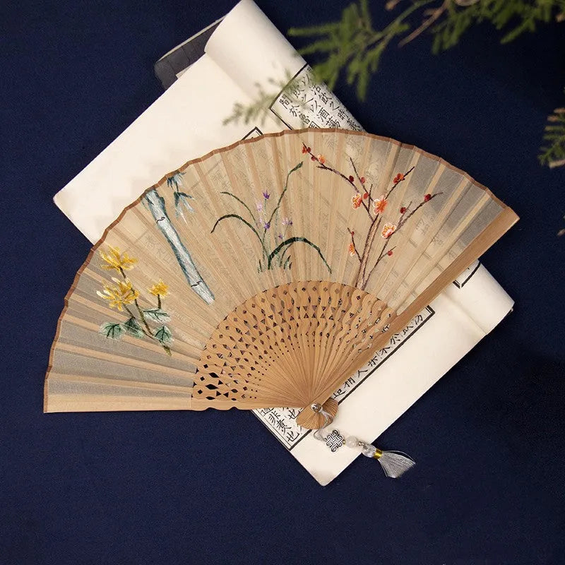 Bamboo frame silk embroidered folding fan showing intricate traditional patterns with folded and open positions