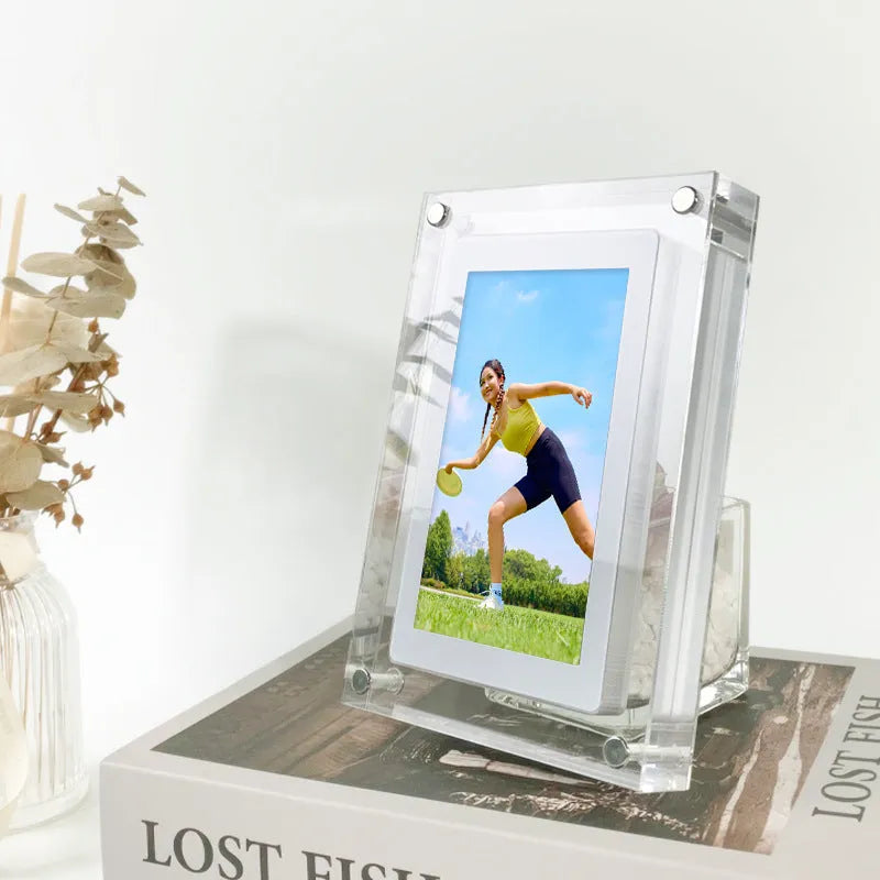 White vertical digital picture frame with acrylic casing on a table, showing a family photo on screen.