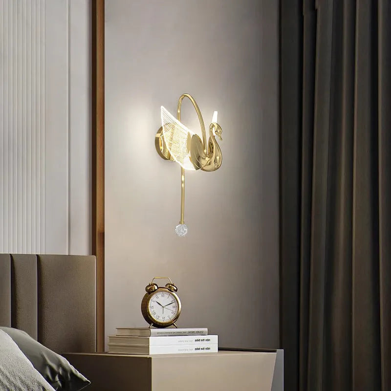 Modern gold swan-shaped wall lamp with white acrylic shade mounted on a wall.