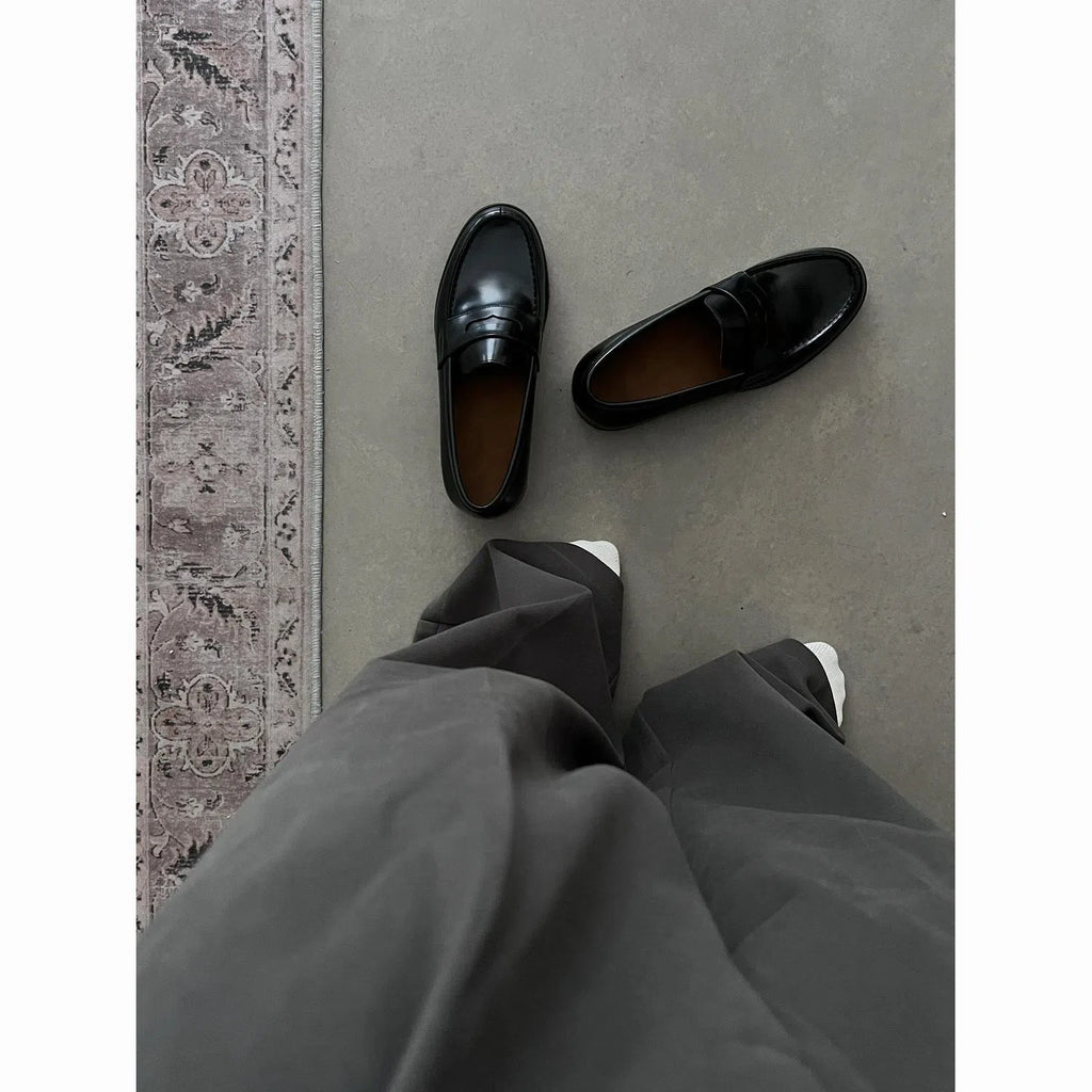 Men's black leather loafers with stitched seams, square heel, and vulcanised rubber sole on display