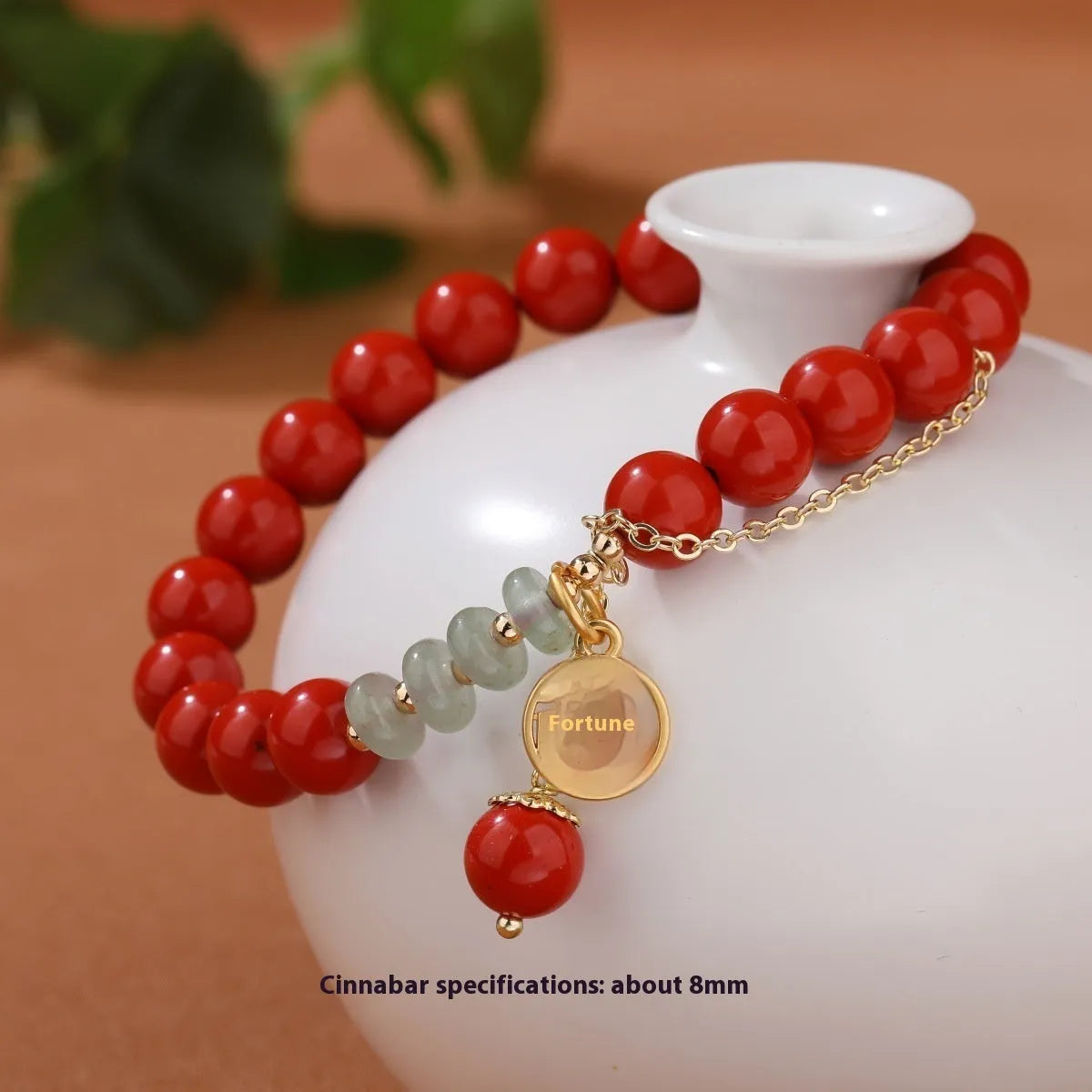 Close-up of a red cinnabar women's bracelet with a Fu character, jade spacer beads, and a small red tassel.