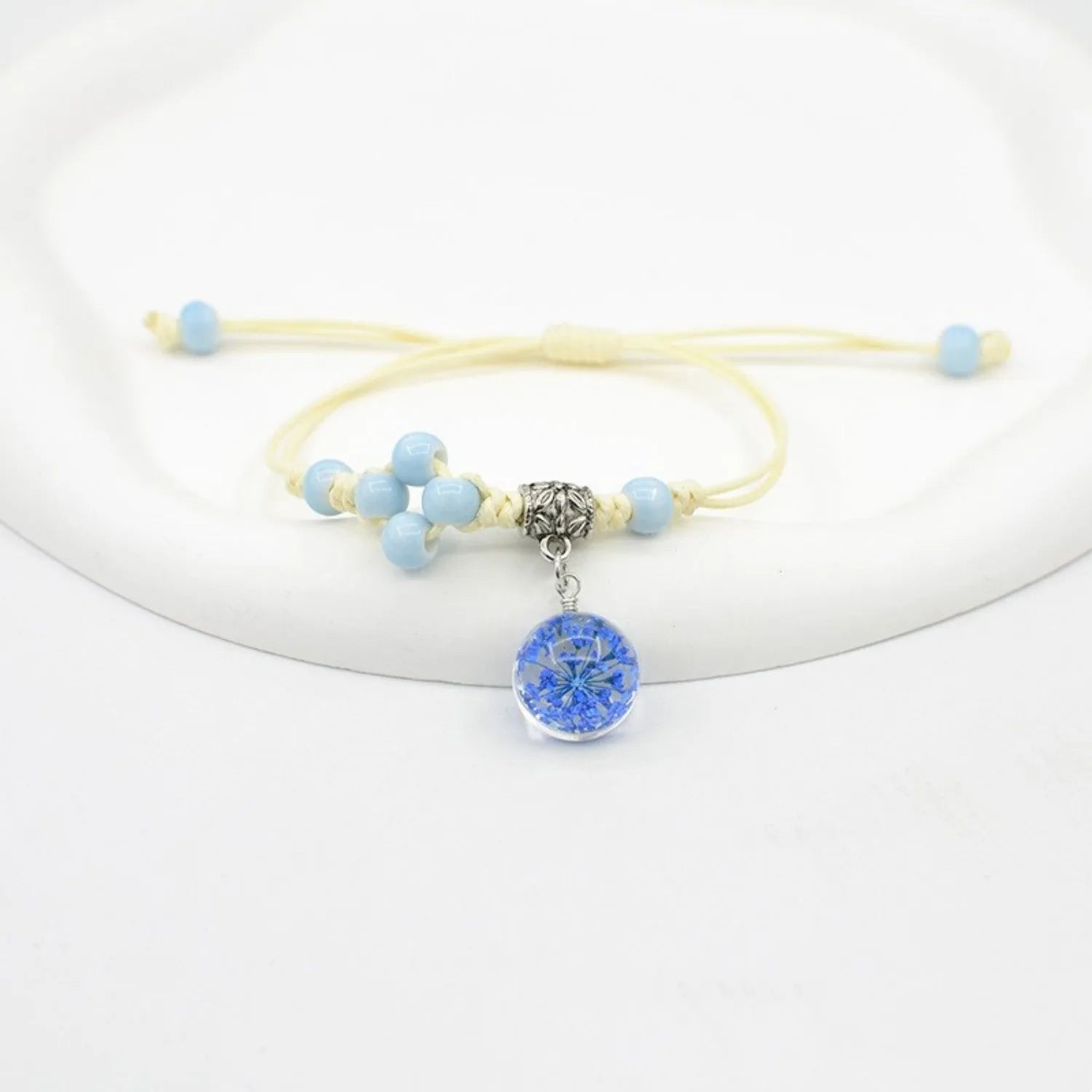 Close-up of a hand-woven glass bracelet with large 1.4cm beads containing real dried flowers in various colours.
