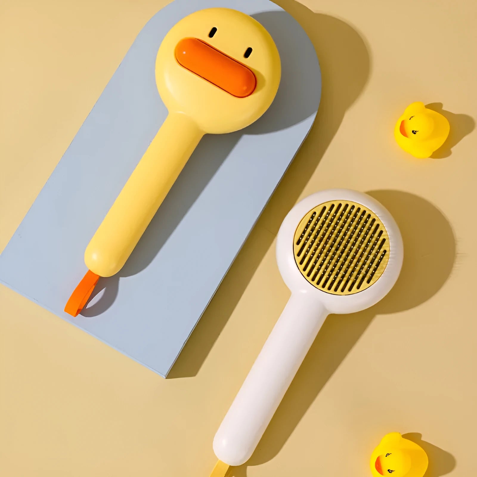 Small yellow duck-shaped pet grooming comb with open-section needle brush design for cat and dog hair removal