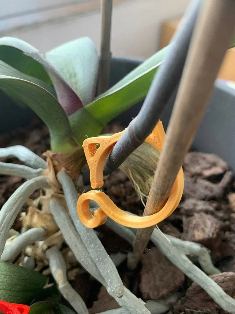 Cat-shaped plastic plant clip in gardening setting with colour options