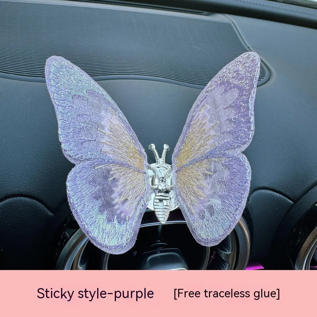 Fabric embroidered butterfly car air vent decoration in multiple colour options on a dashboard.