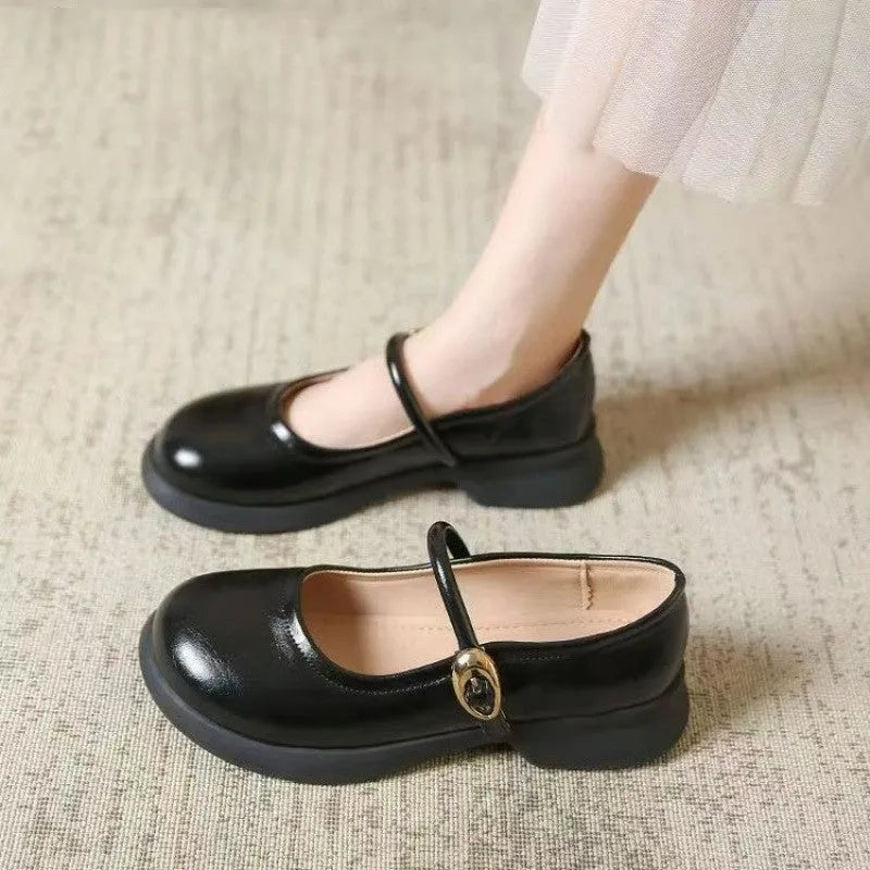 Black leather shoes with skull pattern, round toe, and a wedge heel on a rubber sole.