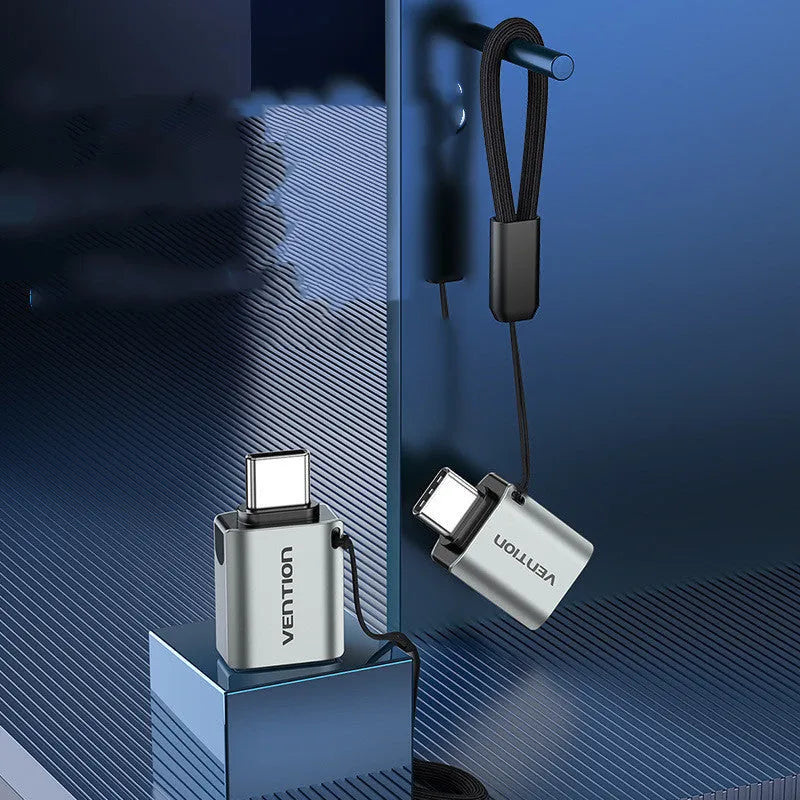 Grey aluminium USB 3.0 OTG adapter with USB-C male and USB-A female connectors and a lanyard.