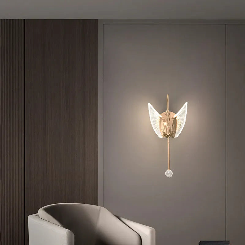 Modern gold swan-shaped wall lamp with white acrylic shade mounted on a wall.