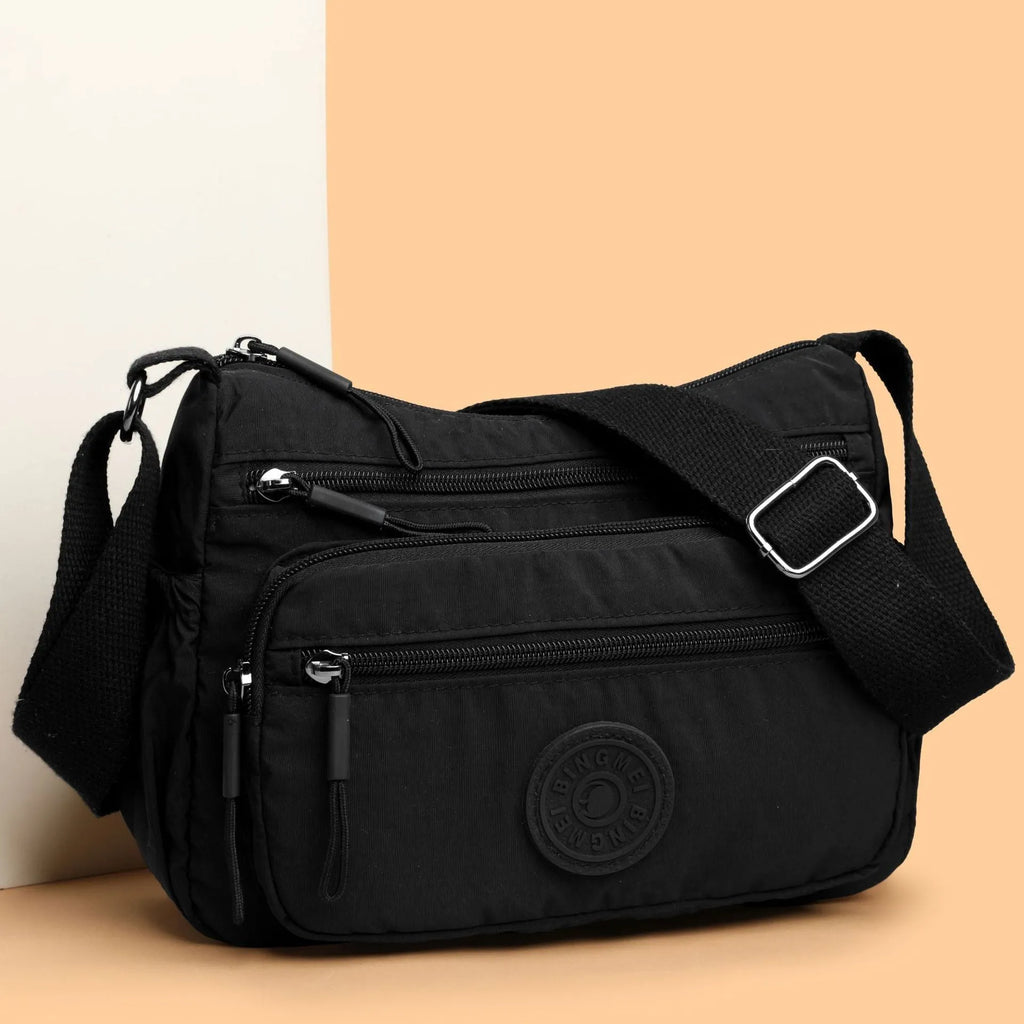 Grey water-repellent nylon crossbody bag showing outer pocket and internal organiser compartments.