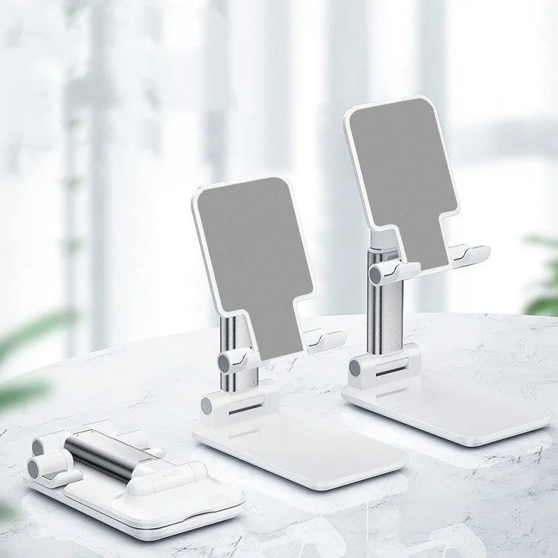 White folding telescopic mobile phone bracket holding a smartphone on a desktop.