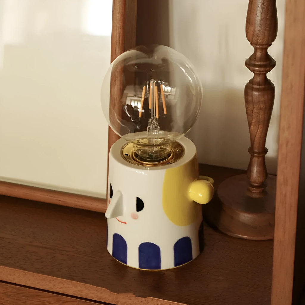 Handmade ceramic table lamp with a white ball headlight shade on a wooden table.