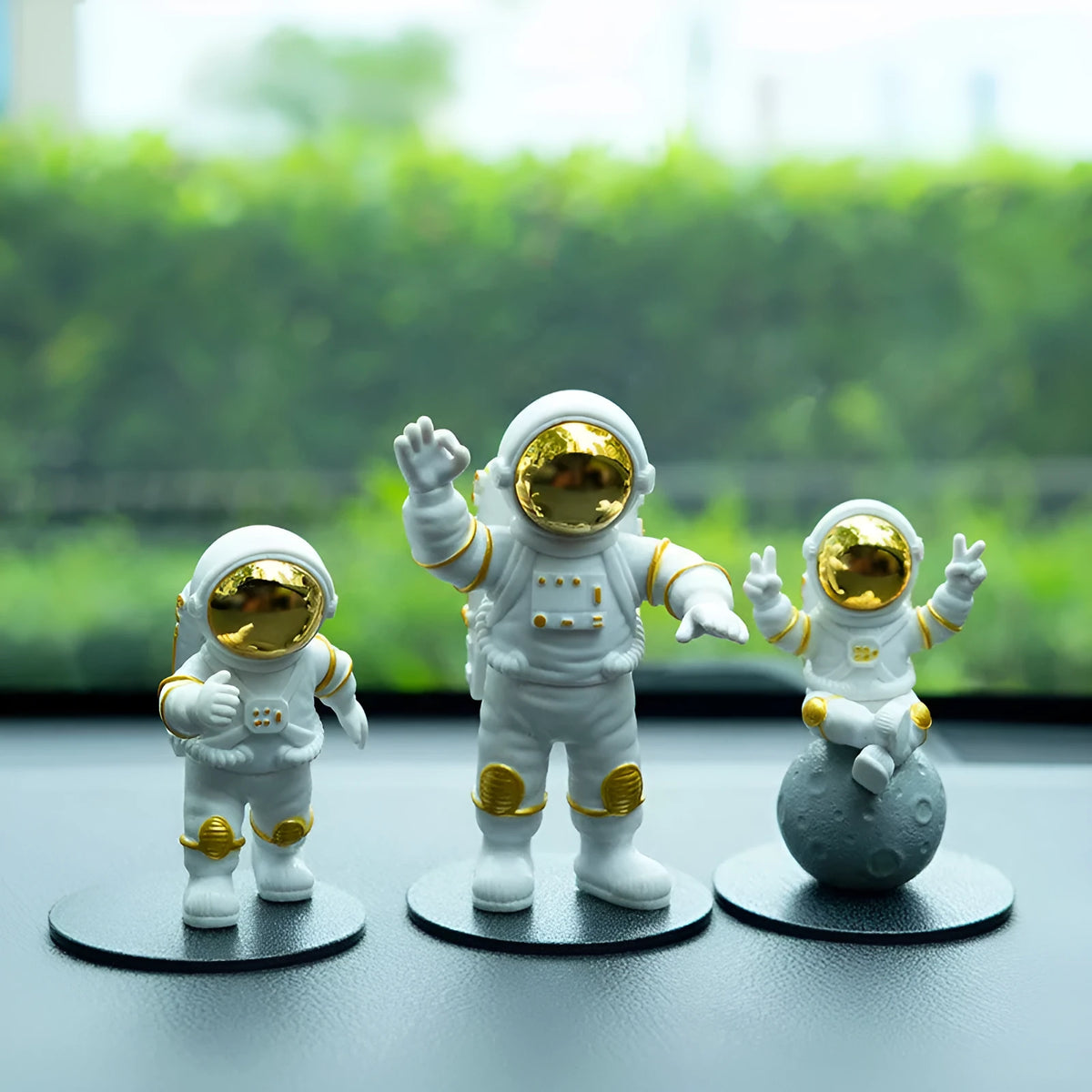 Three resin astronaut figurines for car dashboard decoration, gold finish, placed on dashboard