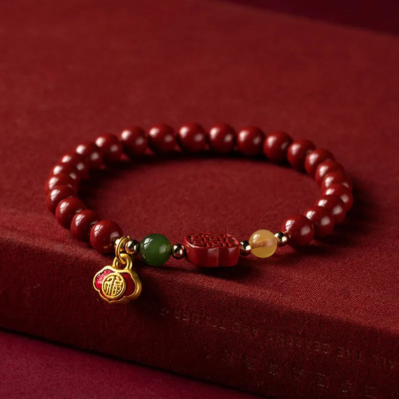 Emperor sandstone bracelet with fu charm on wrist, showing cinnabar and stone beads.