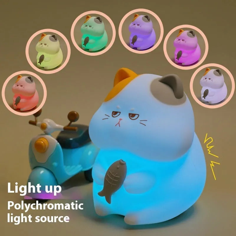 Small yellow Greedy Cat cartoon night light on a desktop, showing fish theme and compact size.