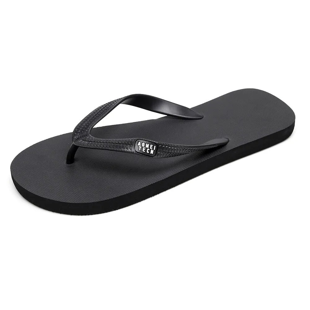 Men's black flip-flops with a textured rubber sole and EVA foam upper on a sandy beach.