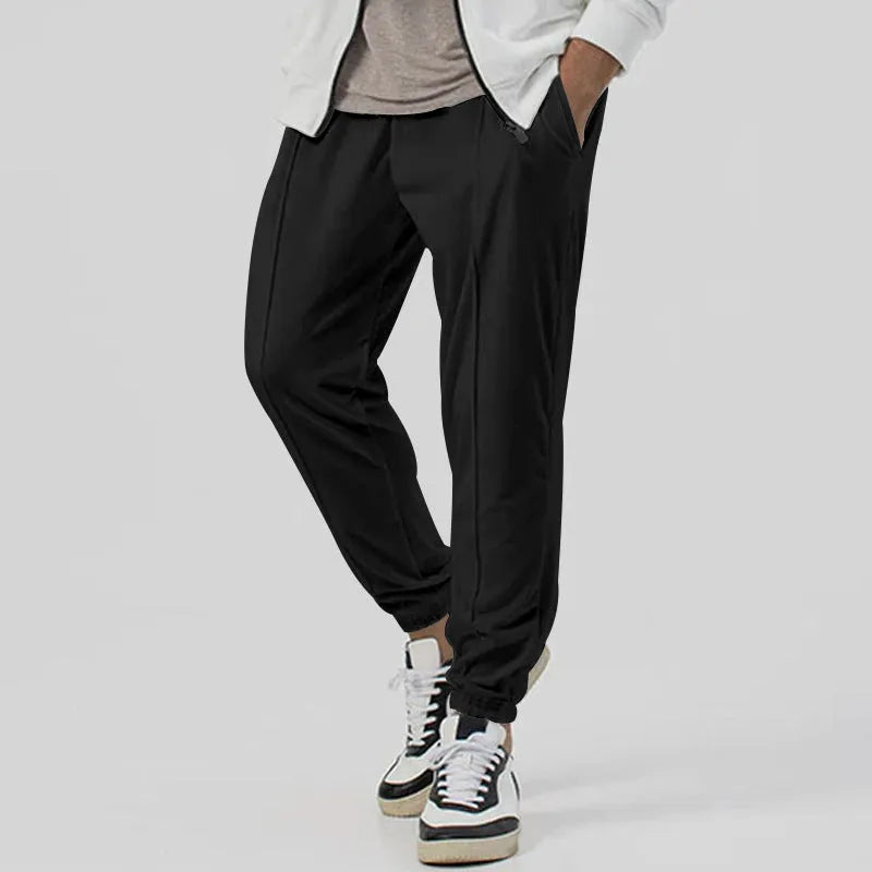Man wearing grey loose tapered cotton blend track sweatpants with a straight leg.