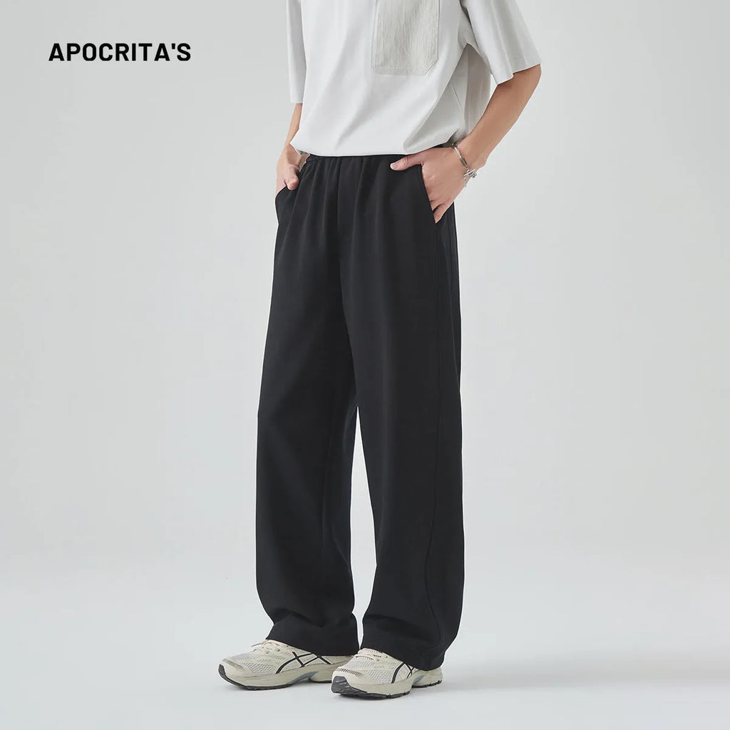 A pair of men's loose-fitting grey casual trousers with a high waist and straight leg on a plain background.