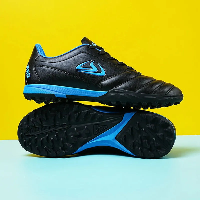 Low-top outdoor soccer shoes in a black and blue broken nails colourway on a turf background.