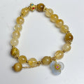 Women's citrine crystal bracelet with gold-plated flower tassel design on wrist.