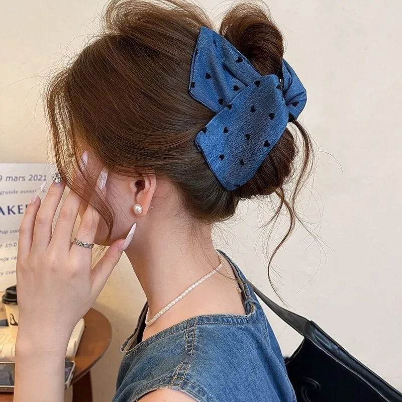 Handmade denim fabric and acrylic hair bow with triangle grip detail on plastic hairpin.