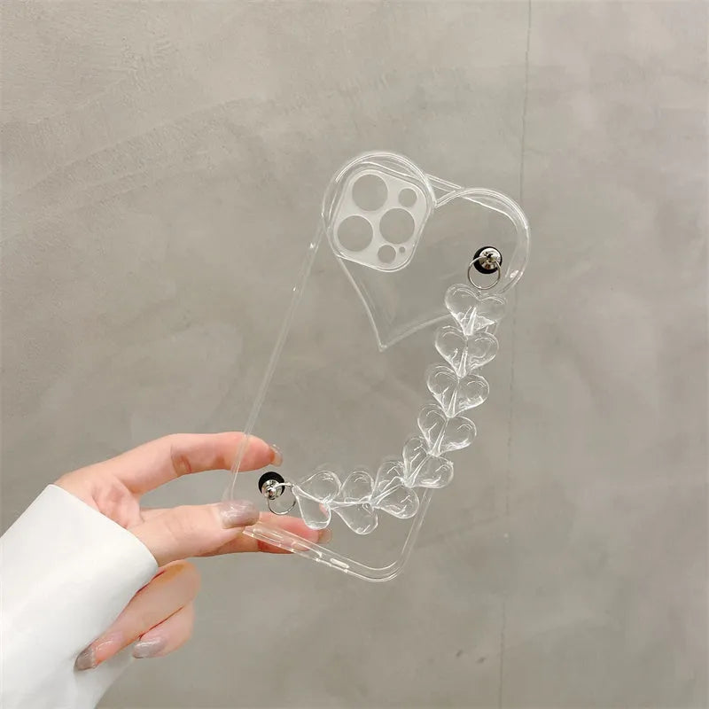 Clear iPhone case with transparent love heart bracelet charm attached, showing soft TPU material.