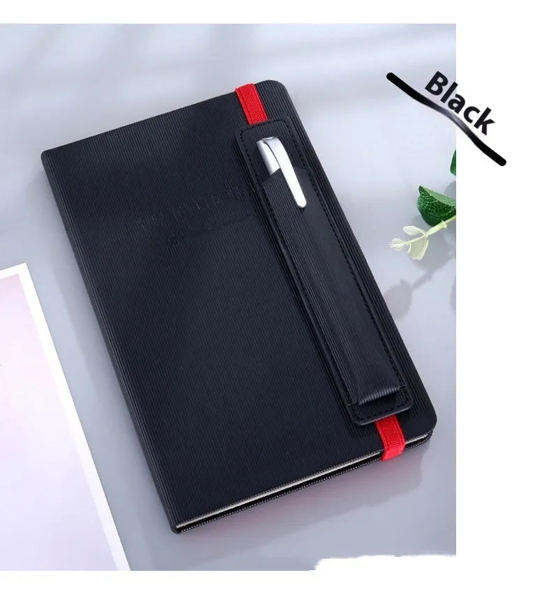 A5 faux leather notebook with pen insert and strap, open on a desk showing lined pages