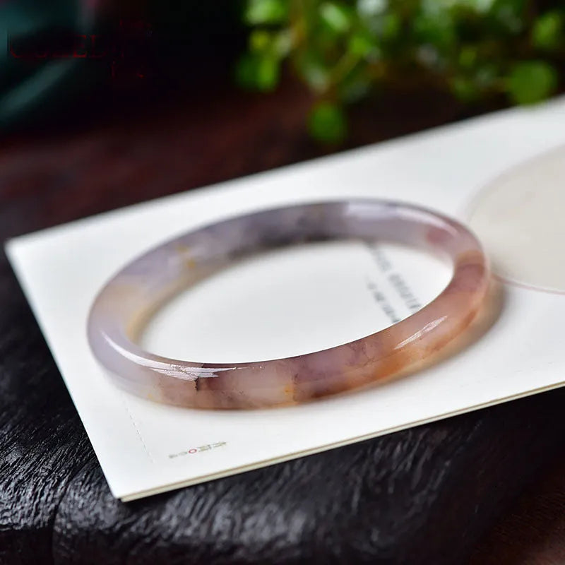 Violet jade bracelet with polished beads shown in flat bar and round bar styles on a wrist.